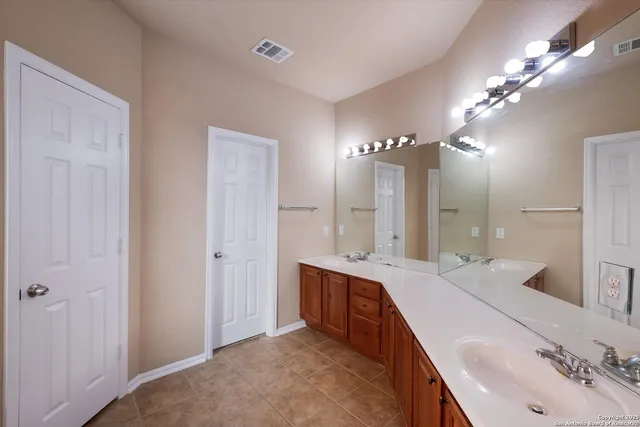 a spacious bathroom with a double vanity sink a large mirror and shower