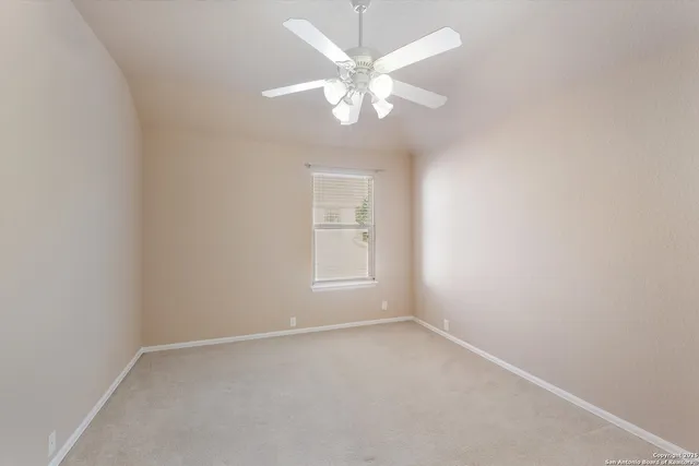 en empty room with windows and chandelier fan
