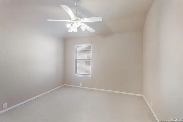 an empty room with a chandelier fan and windows