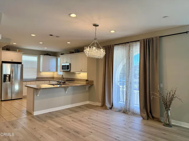 a kitchen with stainless steel appliances granite countertop a refrigerator a stove and a wooden floors