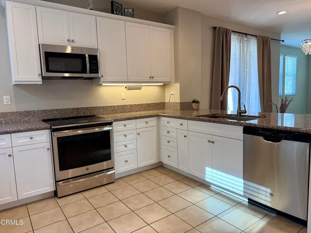 a kitchen with granite countertop white cabinets and stainless steel appliances