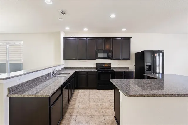 a kitchen with granite countertop stainless steel appliances a sink a stove a microwave a counter top and cabinets