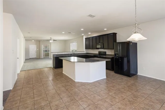 a large kitchen with kitchen island granite countertop a stove top oven a sink and a refrigerator