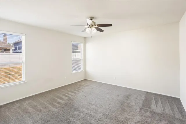 an empty room with windows and fan