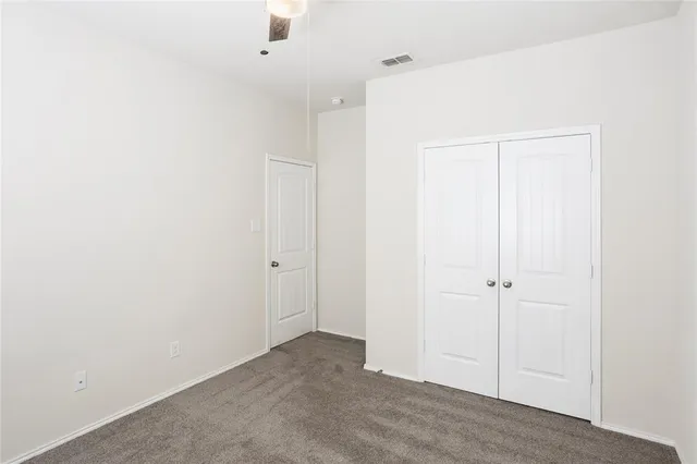 an empty room with a window and a ceiling fan