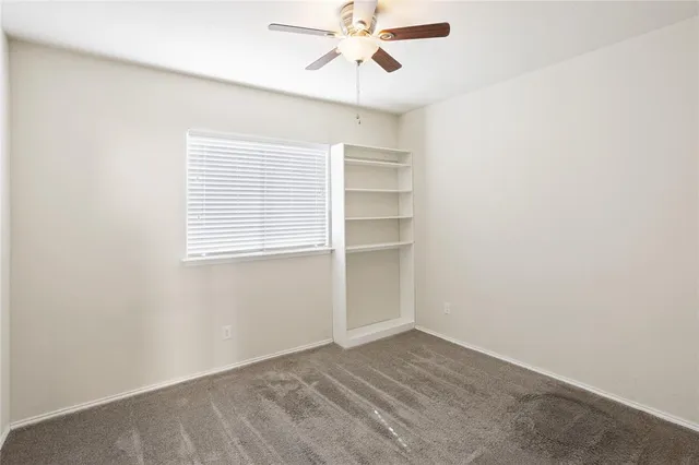 an empty room with a ceiling fan and window