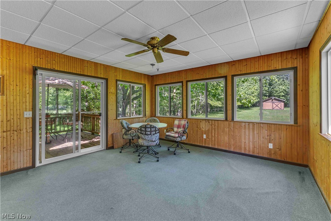 6635 Taylor Road Painesville, OH 44077 - Photo 11 of 41 Sunroom featuring wood-paneled walls and a sliding glass door opening to an outdoor deck