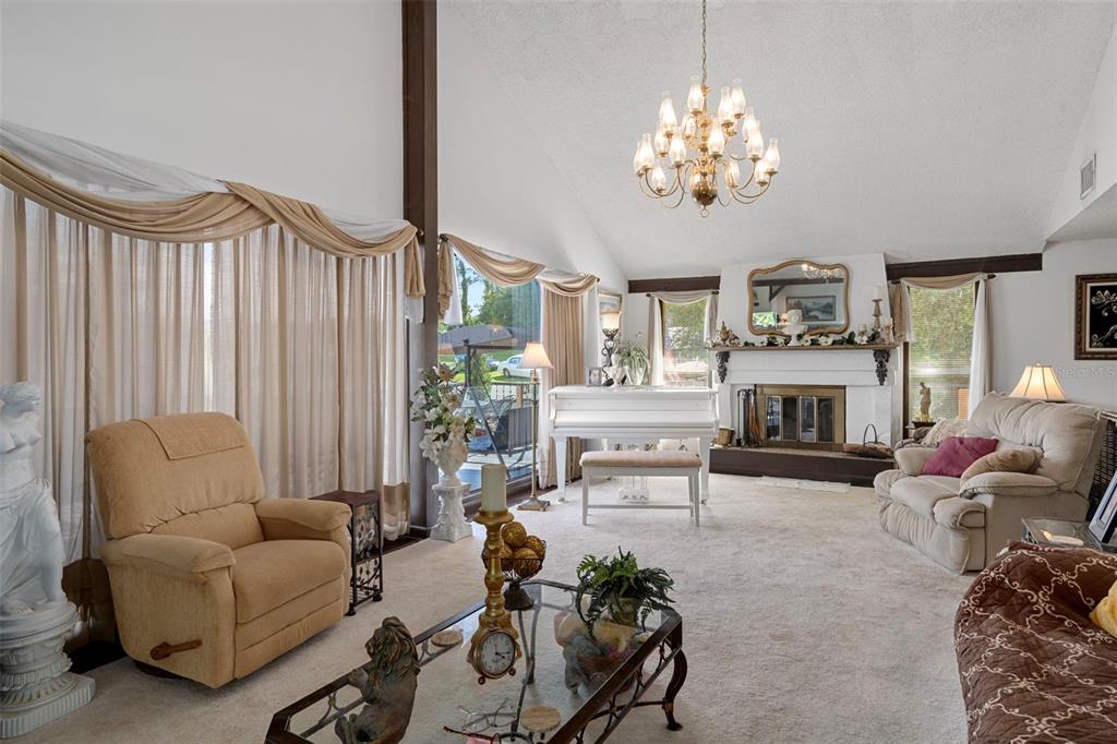 25927 Old Spring Lake Road Brooksville, FL 34601 - Photo 15 of 60 a living room with furniture a fireplace and a chandelier