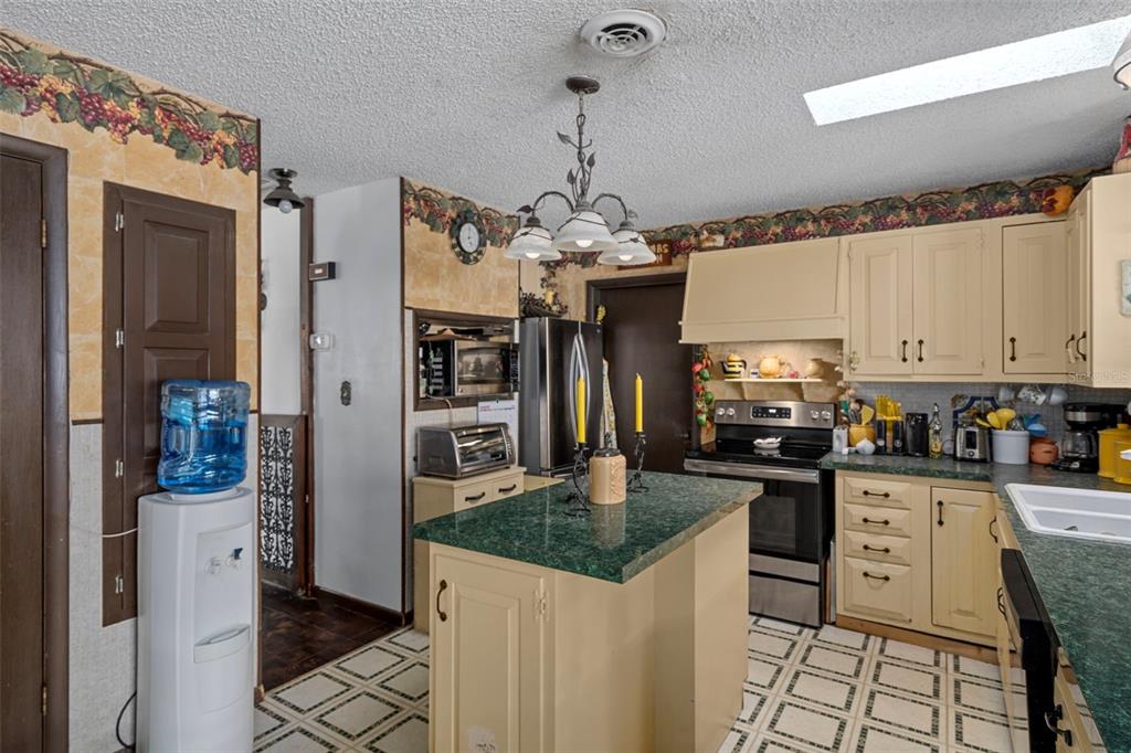 25927 Old Spring Lake Road Brooksville, FL 34601 - Photo 23 of 60 a kitchen with granite countertop a sink stove and refrigerator