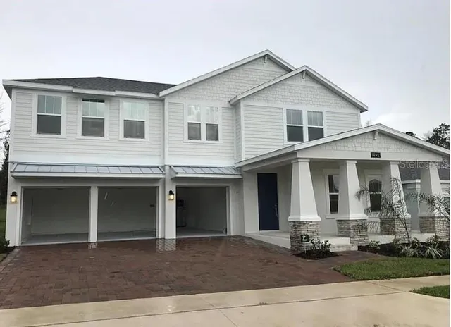 a view of a white house with large windows and a yard with plants