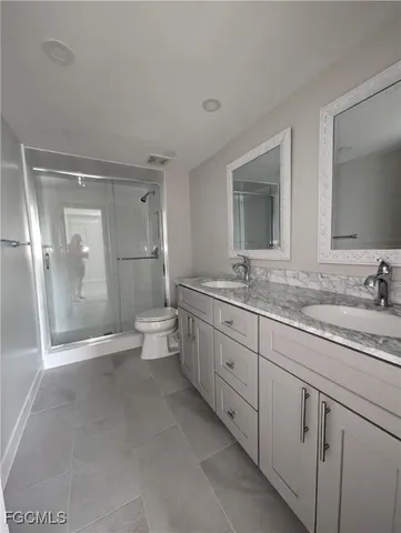 a bathroom with a granite countertop sink mirror and toilet