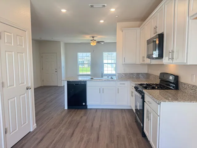 a kitchen with stainless steel appliances granite countertop a stove a sink and a microwave