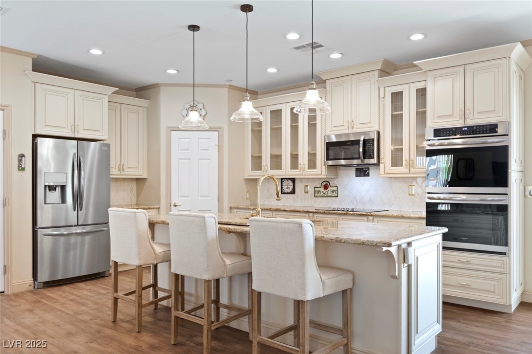 5315 North Fort Apache Road Las Vegas, NV 89149 - Photo 20 of 46 Kitchen featuring stainless steel appliances including a Frigidaire Model N# FGET3069UF Gallery 30'' Double Electric Wall Oven With Air Fry, decorative cabinets, recessed lighting, and an island with a Gold-Tone Sink.