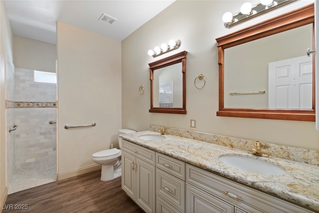 5315 North Fort Apache Road Las Vegas, NV 89149 - Photo 28 of 46 Secondary Bathroom featuring double vanity, toilet, a walk in shower, Luxury Vinyl Plank finished floors, and baseboards.