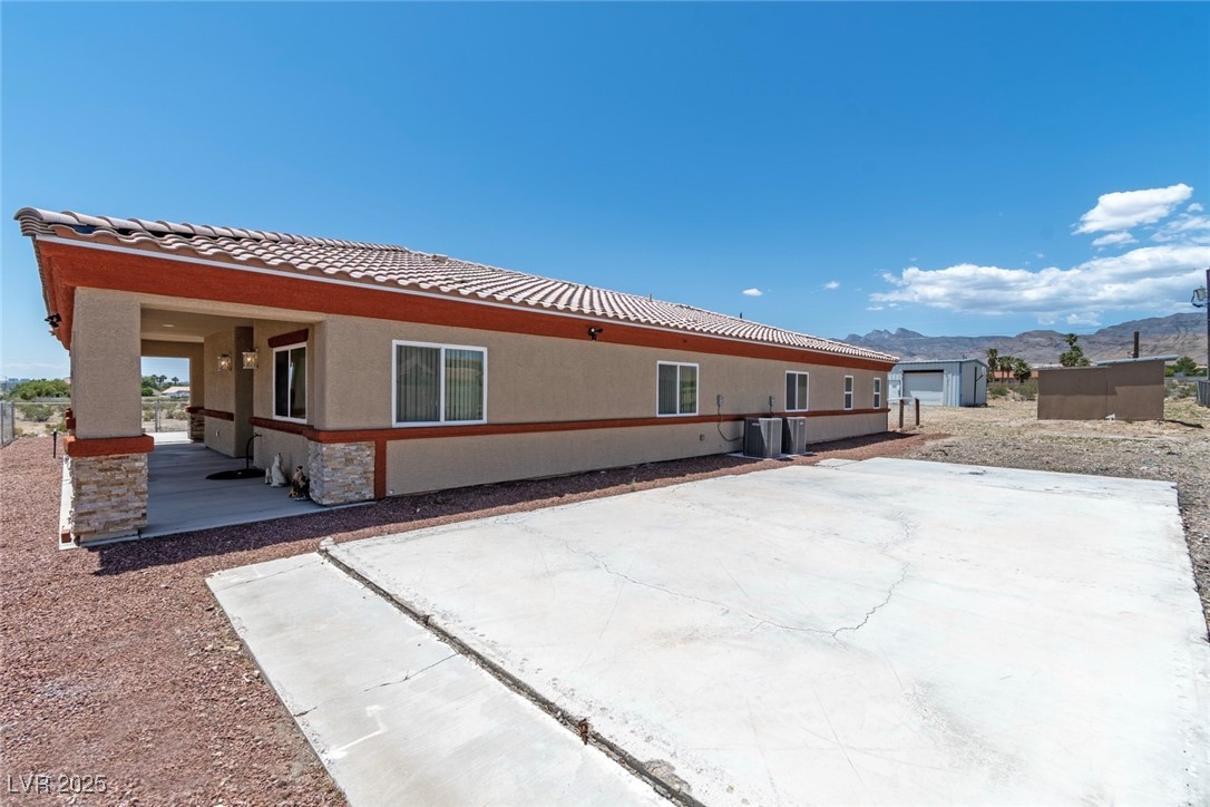 5315 North Fort Apache Road Las Vegas, NV 89149 - Photo 37 of 46 North Side view of house with a Clay Terra Cotta Tiled roof, and stucco siding. Extra concrete Flooring which could be covered with Red Rock, or possible shedding.