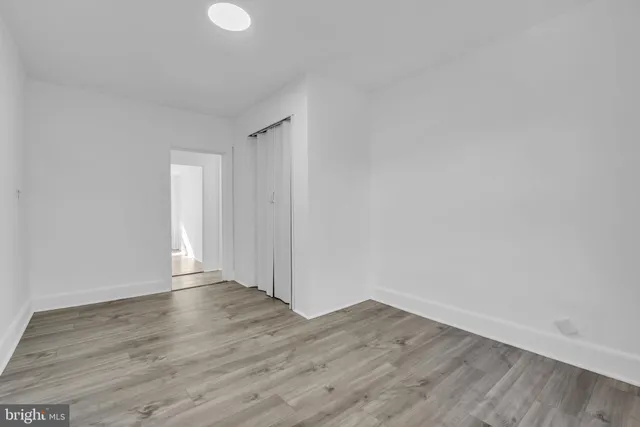 a view of an empty room with wooden floor and white walls