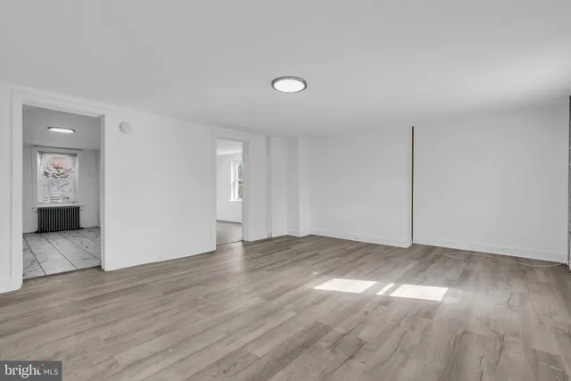 an empty room with wooden floor & windows and bathroom