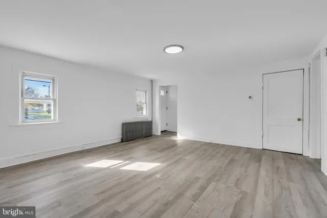 a view of an empty room with wooden floor and window
