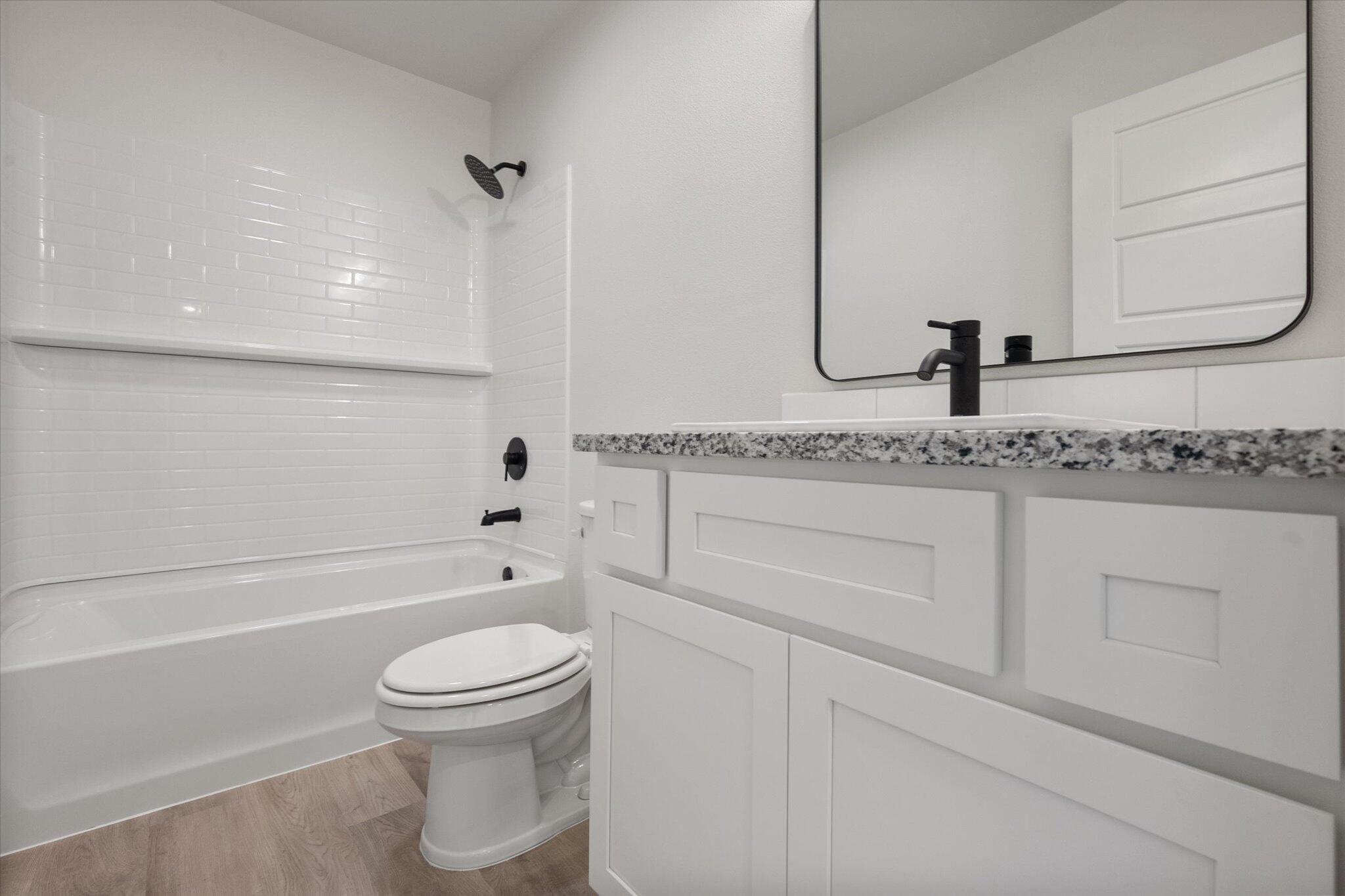 1603 North Clinton Avenue Lubbock, TX 79416 - Photo 8 of 14 a bathroom with a granite countertop toilet a sink and a bathtub