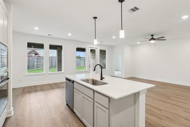 a kitchen with a sink chandelier and wooden floor