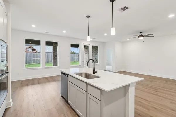 a kitchen with a sink chandelier and wooden floor
