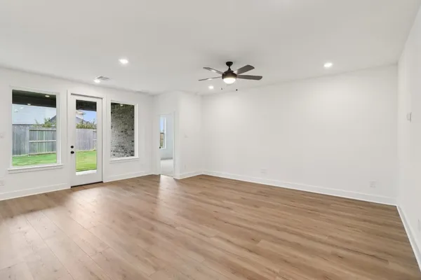 a view of an empty room with a window and wooden floor