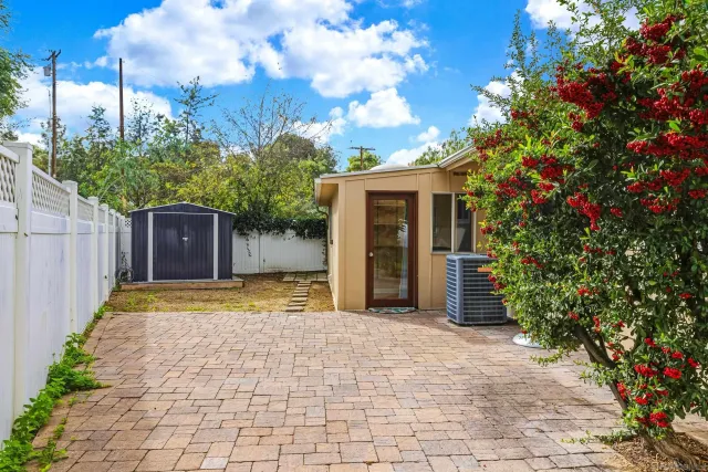 a view of a backyard with table and chairs potted plants and large tree