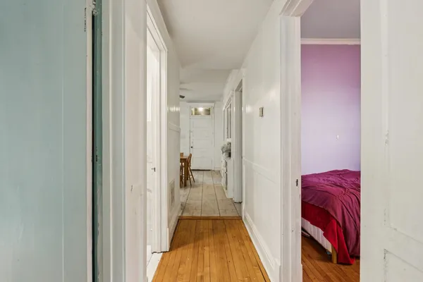 a view of a hallway with wooden floor and a bathroom