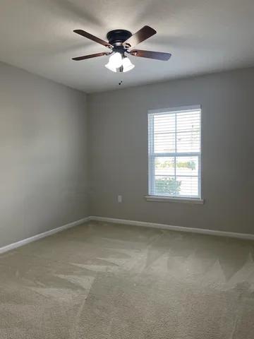 an empty room with a chandelier fan and windows