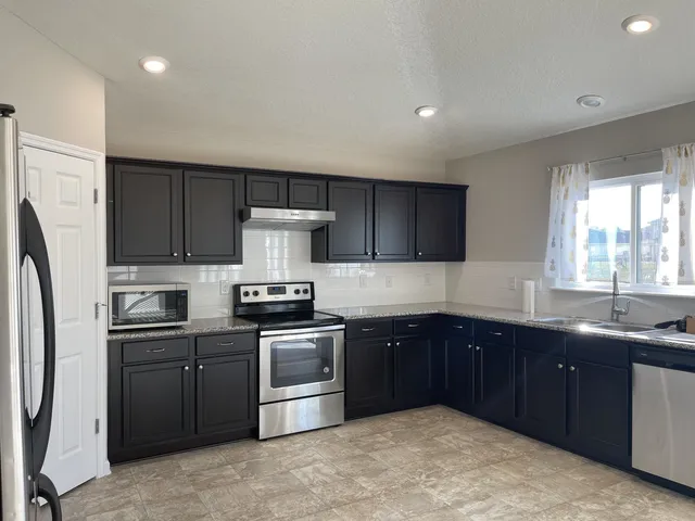 a kitchen with stainless steel appliances granite countertop a sink a stove a refrigerator and cabinets