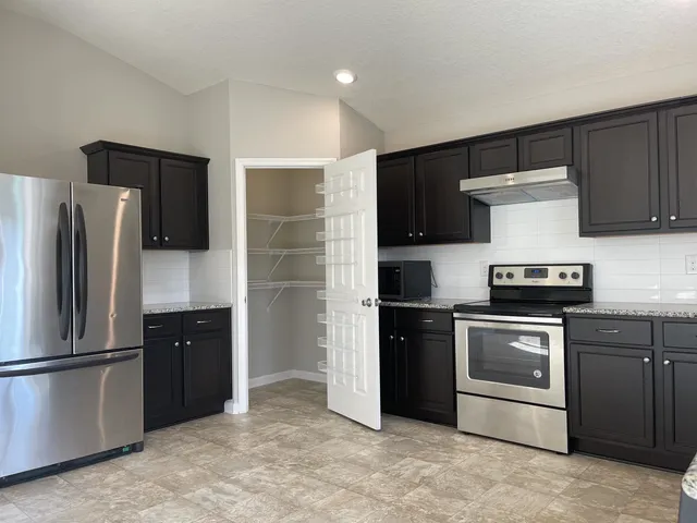 a kitchen with stainless steel appliances granite countertop a refrigerator and a stove top oven