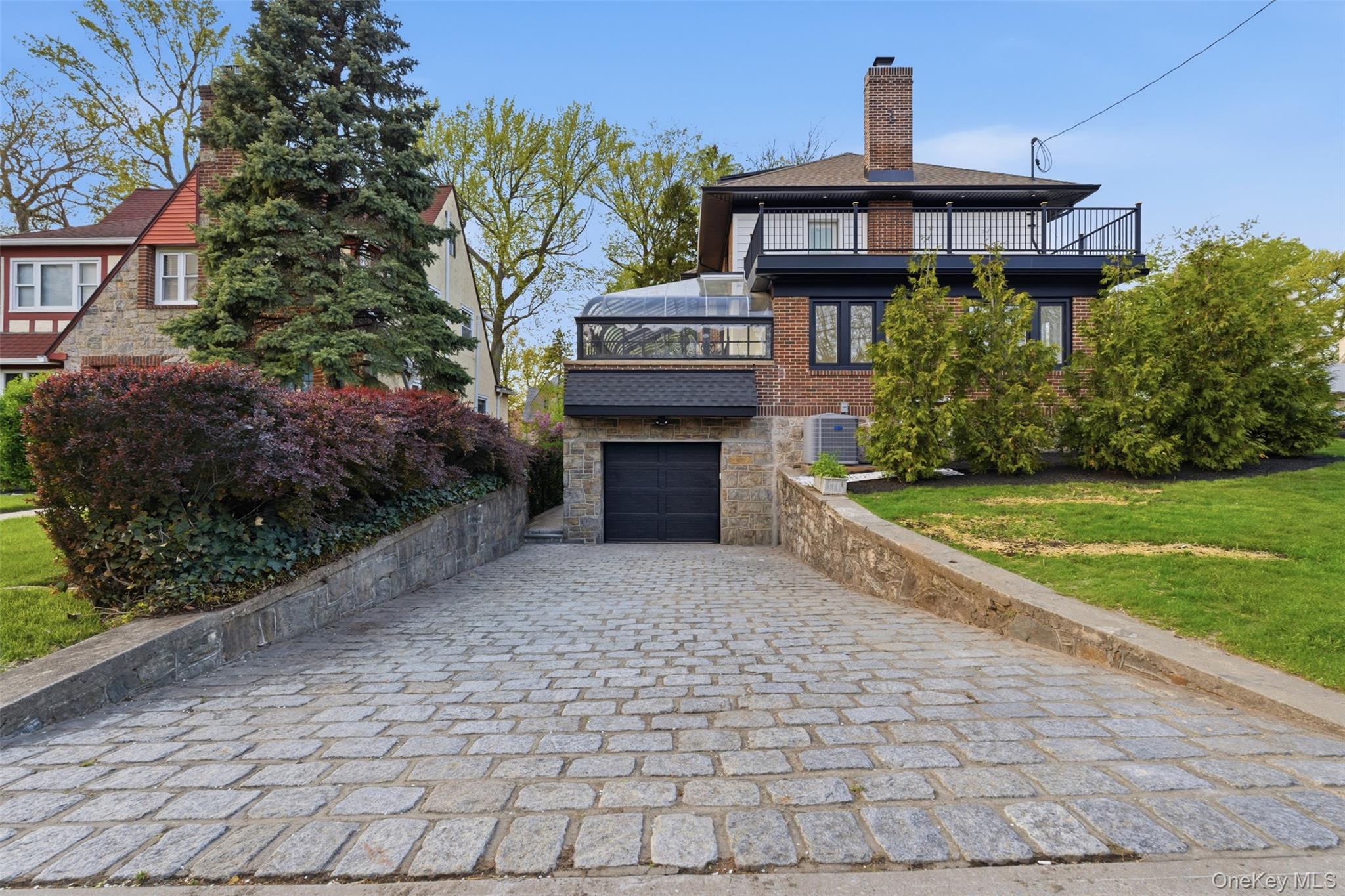 40 Calhoun Avenue New Rochelle, NY 10801 - Photo 36 of 49 Belgian Block driveway leading to an integrated stone and brick facade with a black garage door