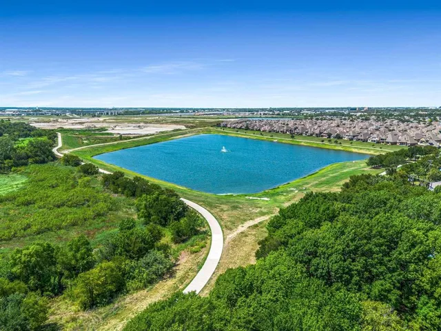 an aerial view of a residential houses with outdoor space and trees all around
