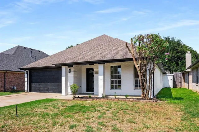 a view of a white house with a large windows and a yard and plants