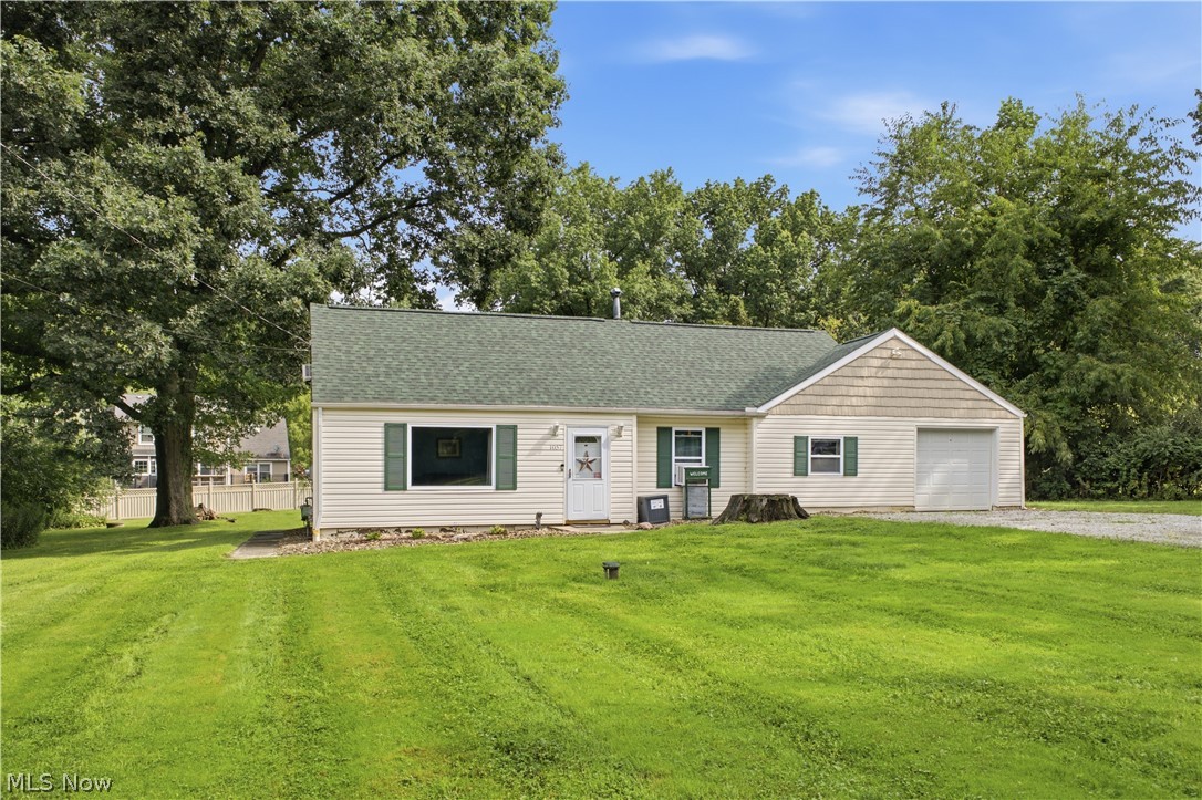 1057 Center Road Clinton, OH 44216 - Photo 2 of 24 Light-colored siding exterior with dark green shutters, a dark green roof, and an attached garage
