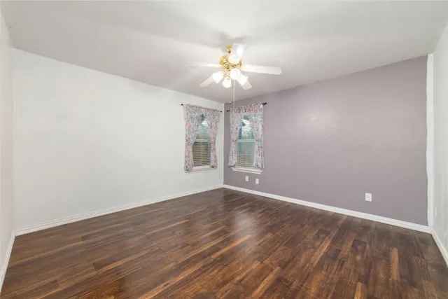 a view of an empty room with window and wooden floor