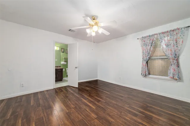 an empty room with wooden floor chandelier fan and windows