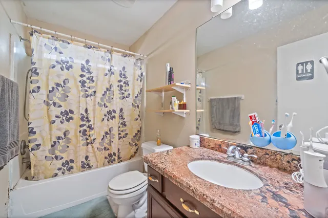 a bathroom with a granite countertop toilet sink and mirror