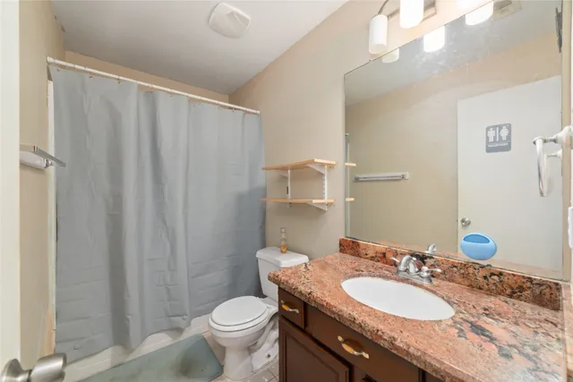 a bathroom with a granite countertop sink and a mirror with toilet