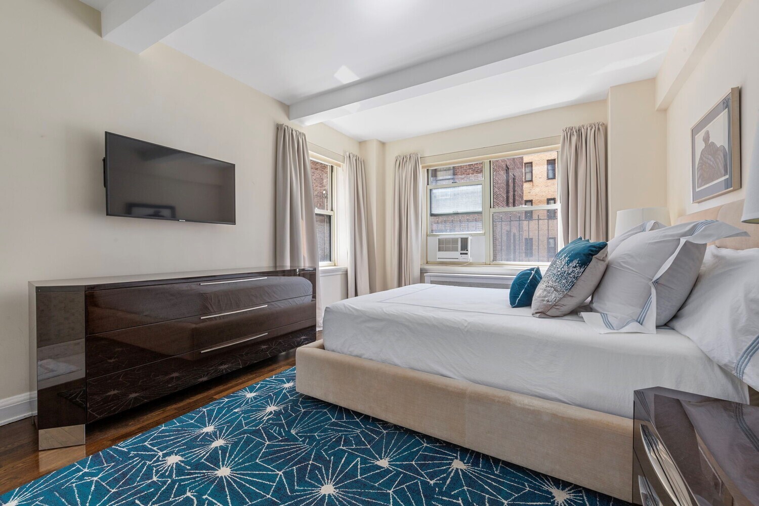 400 East 52nd Street, Unit 7J Manhattan, NY 10022 - Photo 3 of 9 a bedroom with a bed a flat screen tv and a window