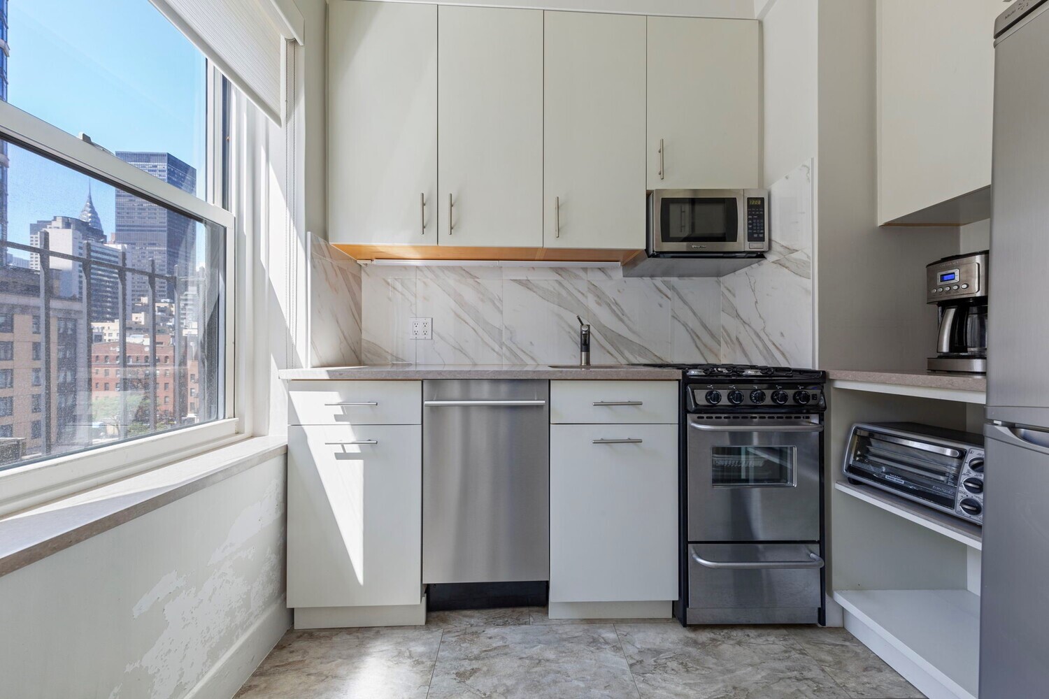 400 East 52nd Street, Unit 7J Manhattan, NY 10022 - Photo 4 of 9 a kitchen with stainless steel appliances and a refrigerator