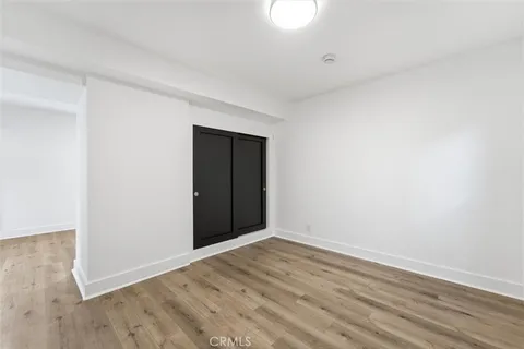 a view of an empty room with wooden floor and closet