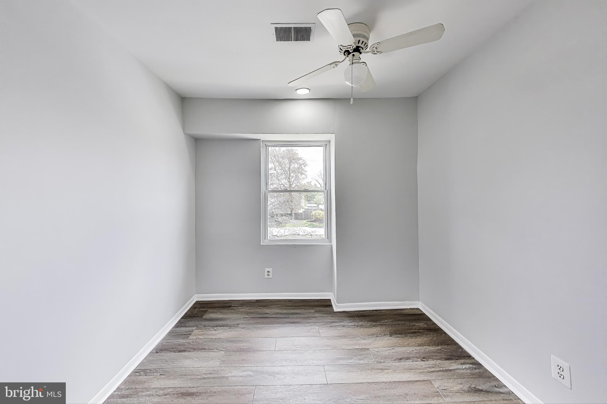 17520 Hoskinson Road Poolesville, MD 20837 - Photo 21 of 31 an empty room with wooden floor ceiling fan and windows