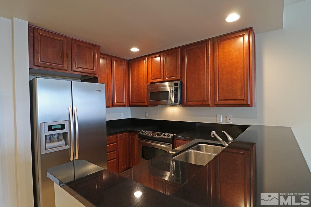 50 North Sierra Street, Unit 706 Reno, NV 89501 - Photo 3 of 24 a kitchen with stainless steel appliances granite countertop a refrigerator a sink and wooden cabinets