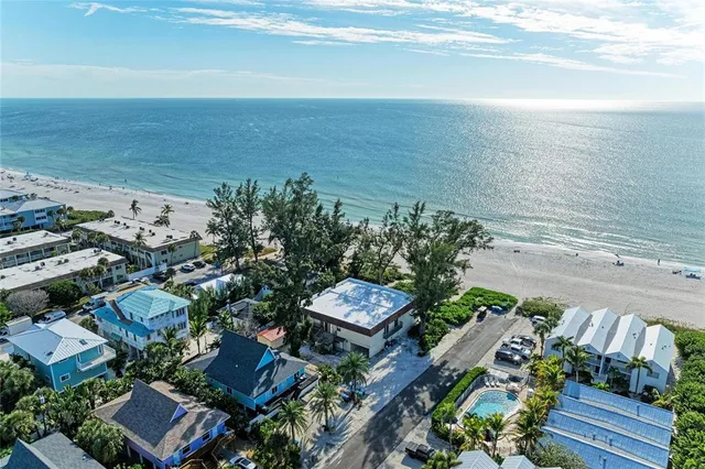 an aerial view of ocean and residential houses with outdoor space