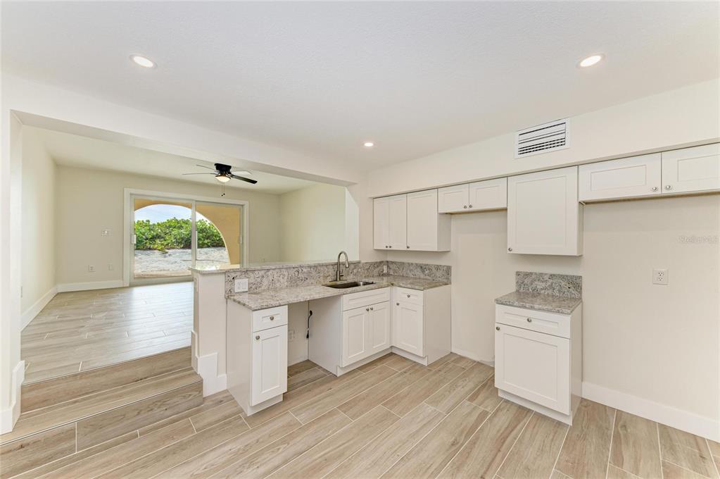 101 73rd Street, Unit 2 Holmes Beach, FL 34217 - Photo 24 of 55 a kitchen with white cabinets and wooden floor