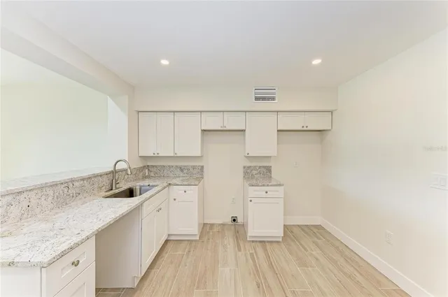 a kitchen with granite countertop a sink white cabinets and a window