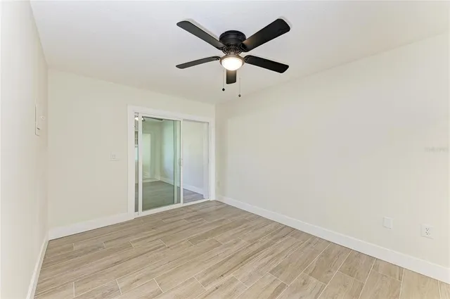 a view of empty room with wooden floor and fan