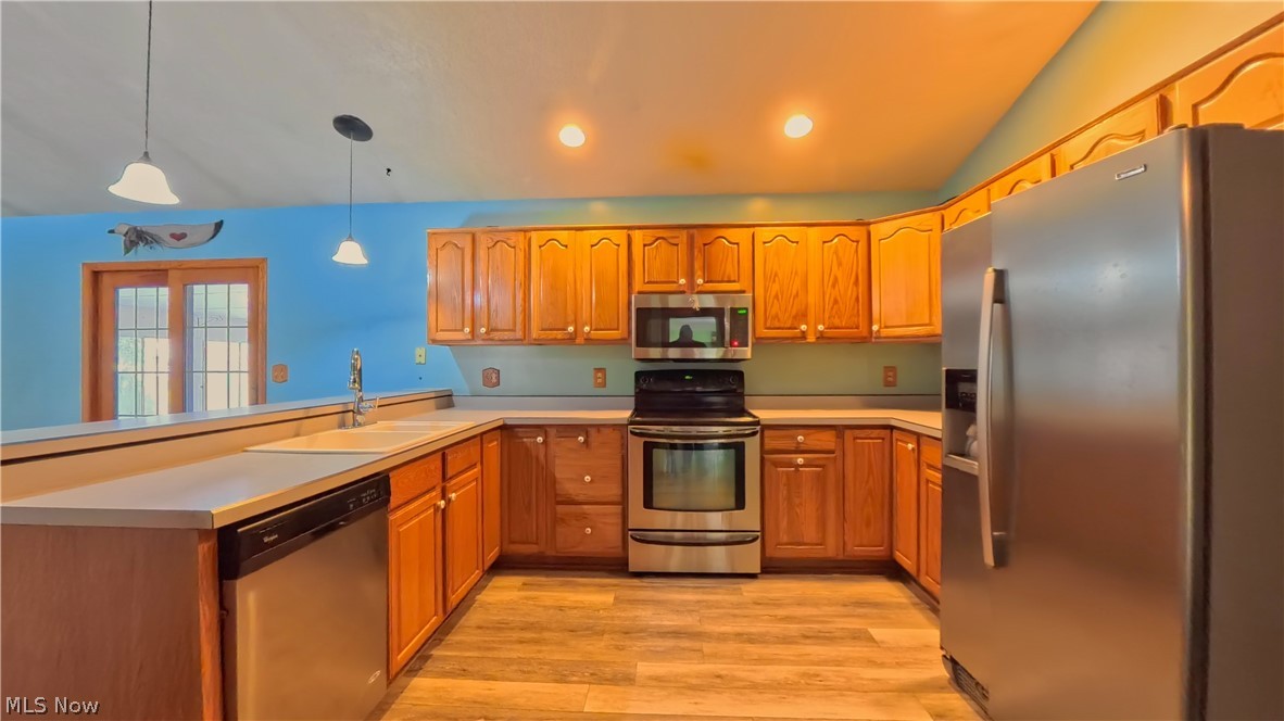 48276 Dyke Road Negley, OH 44441 - Photo 5 of 30 Kitchen featuring stainless steel appliances, wood finish cabinetry, light countertops, pendant lighting, and light wood-style flooring