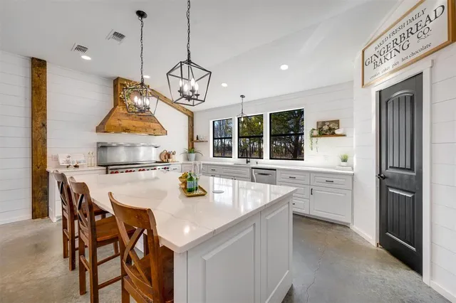 a kitchen with stainless steel appliances granite countertop a sink a stove a dining table and chairs